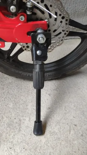 Close-up of the kickstand mounting plate bolted beside the rear wheel of a red kids bike, photographed by a verified buyer